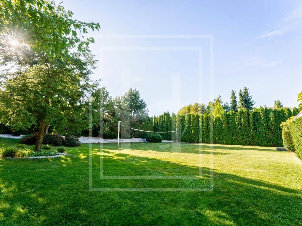 Großer, sonniger Garten mit weitläufiger Rasenfläche und einem Volleyballnetz für sportliche Aktivitäten.