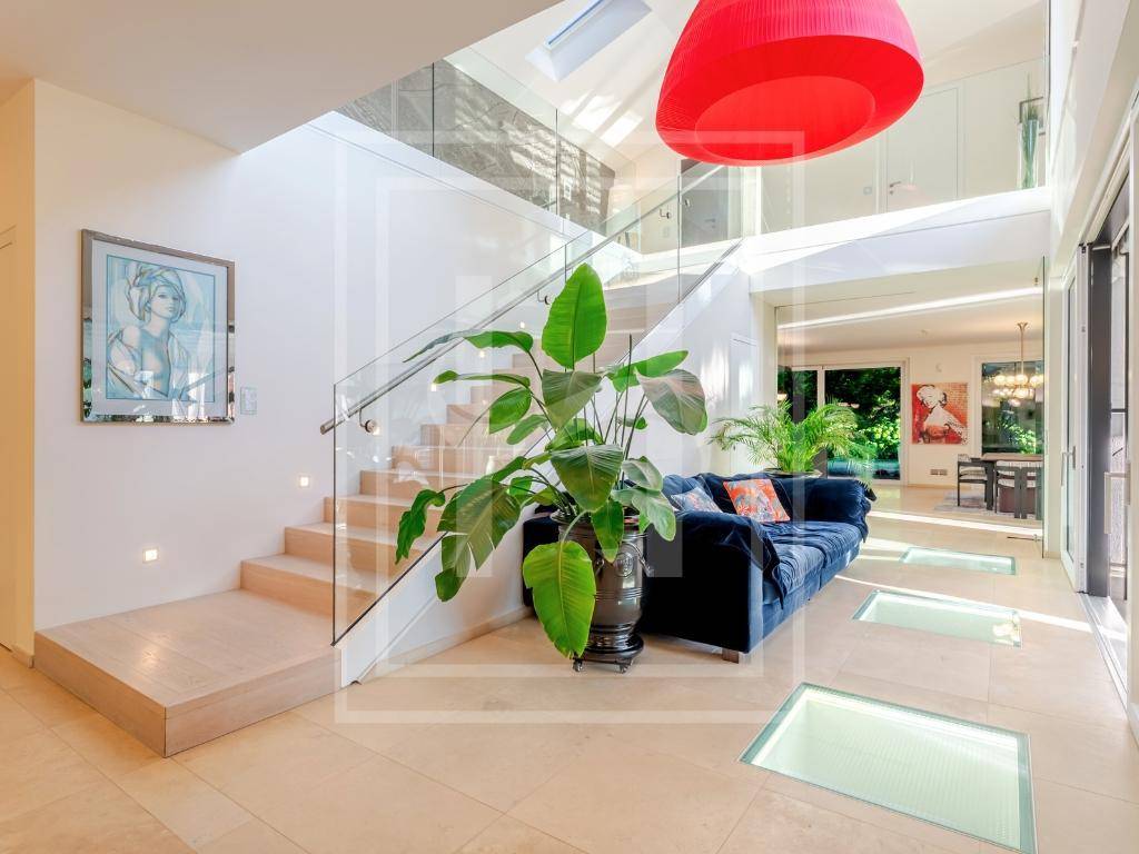 Großzügiger Eingangsbereich mit moderner Treppe, Glasbodenplatten und viel natürlichem Licht.