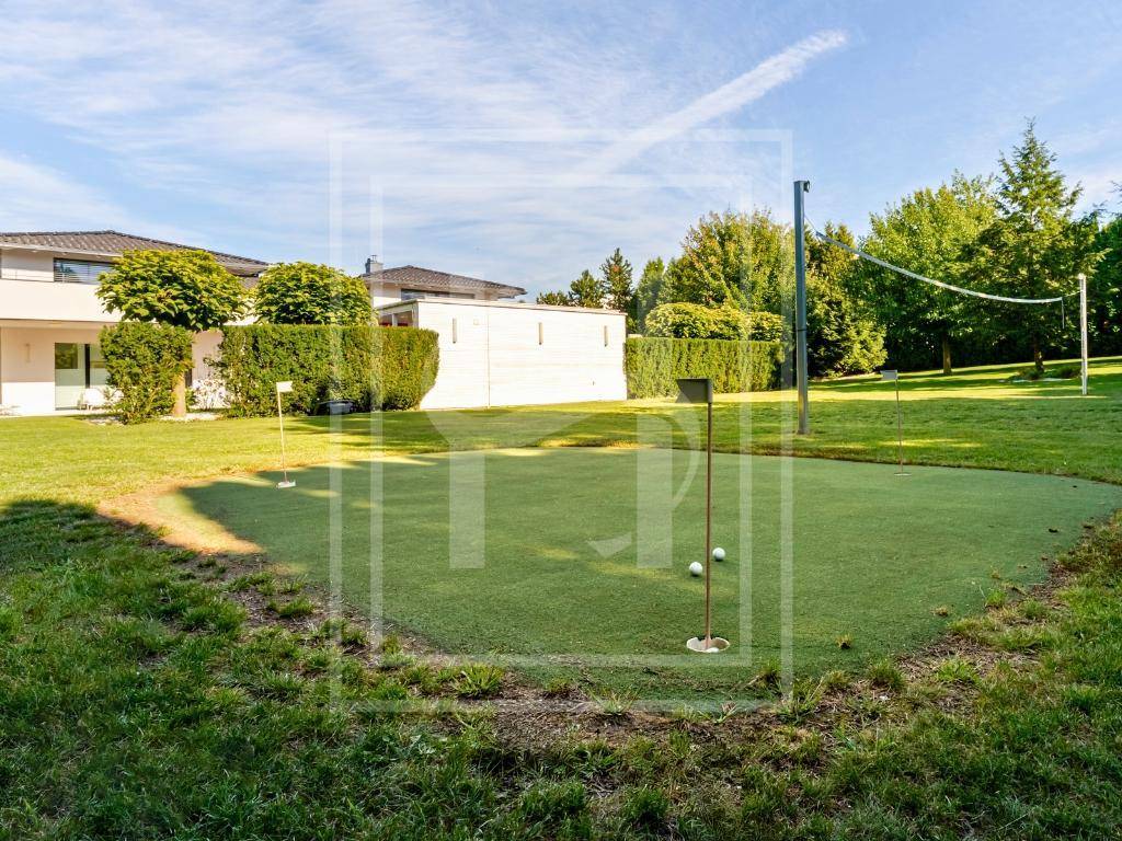 Gepflegter Gartenbereich mit einem Putting Green und einem Volleyballfeld im Hintergrund für Sportbegeisterte.