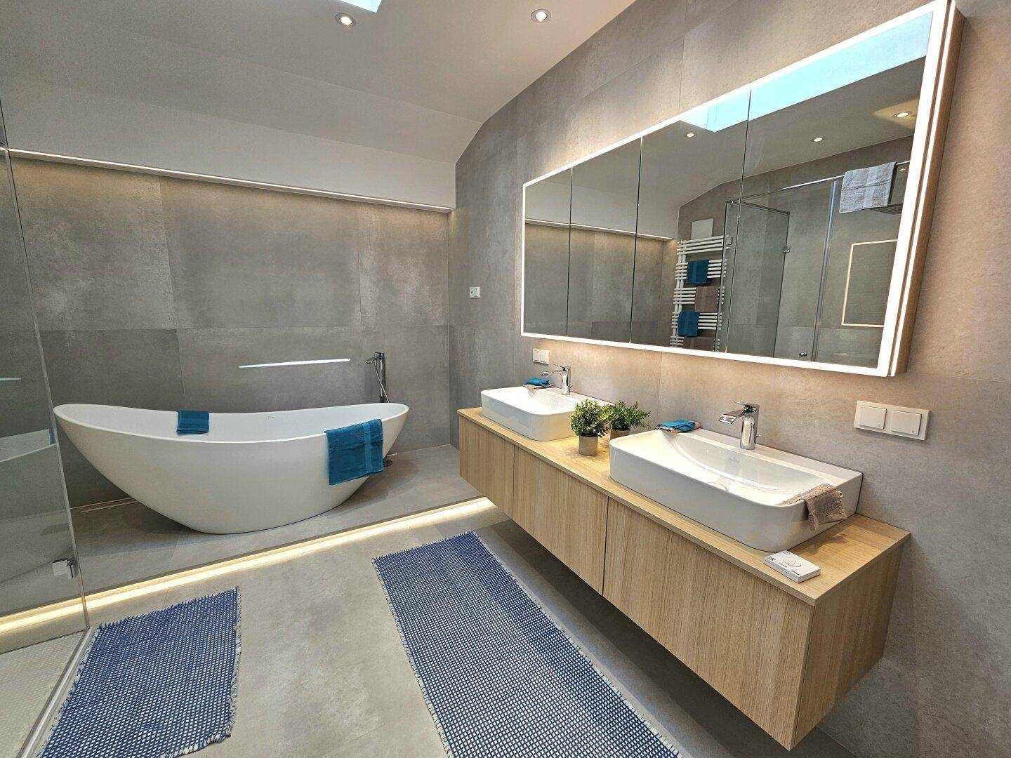 Modernes Badezimmer mit freistehender Badewanne, Doppelwaschbecken und großer Spiegelfläche.