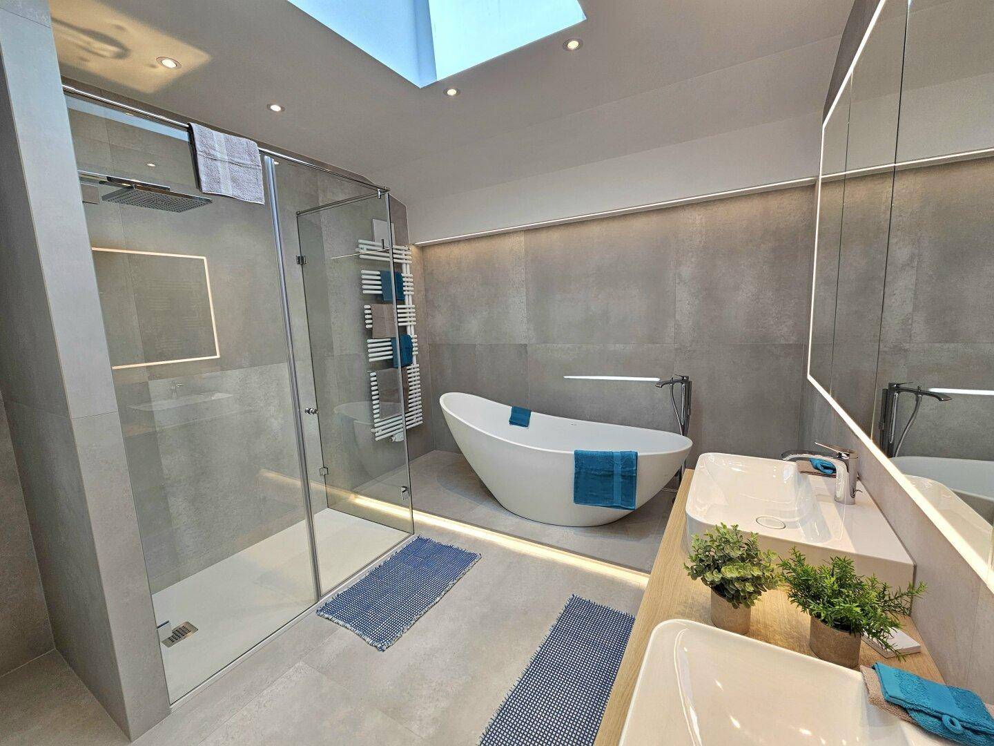 Helles Badezimmer mit begehbarer Dusche, freistehender Wanne und Dachfenster für viel Tageslicht.