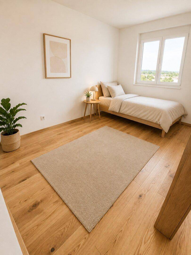 Helles Schlafzimmer mit Holzboden, Einzelbett und großem Fenster für viel Tageslicht und Ausblick ins Grüne.
