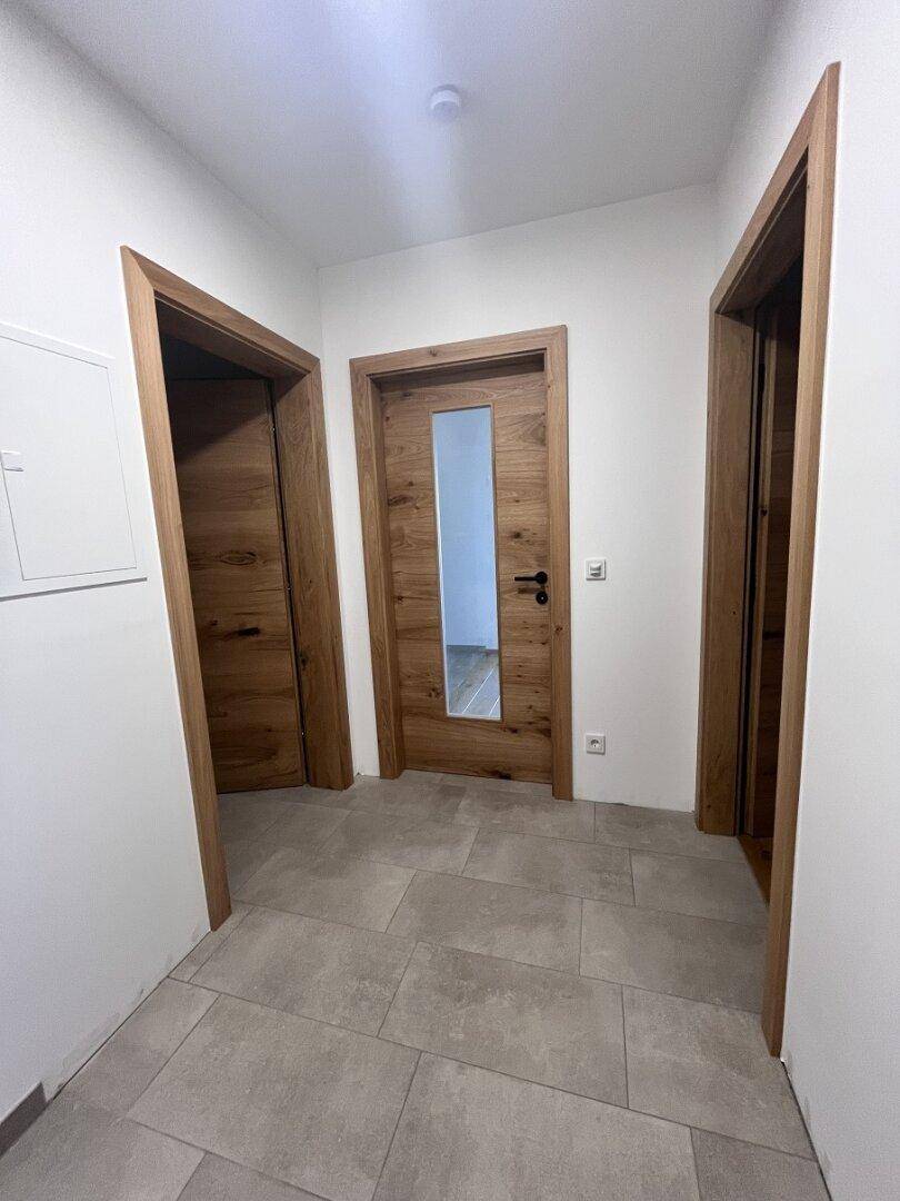 Heller Flur mit modernen Holztüren und Fliesenboden, der zu verschiedenen Räumen der Wohnung führt.