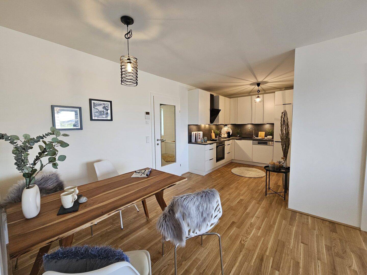 Moderne offene Küche mit weißen Schränken, Holzboden und integriertem Essbereich.