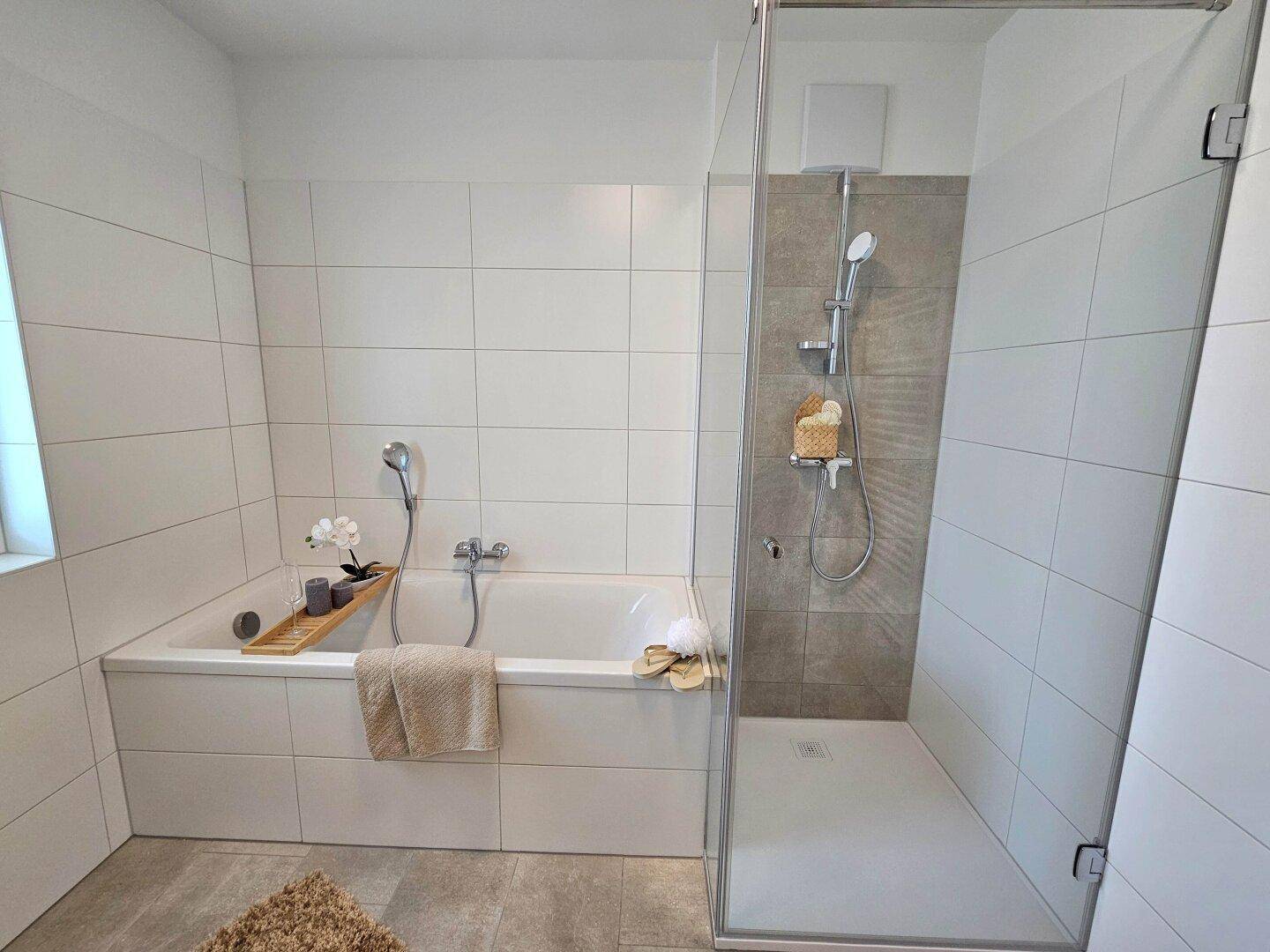 Modernes Badezimmer mit Badewanne, begehbarer Dusche und hellen Fliesen.