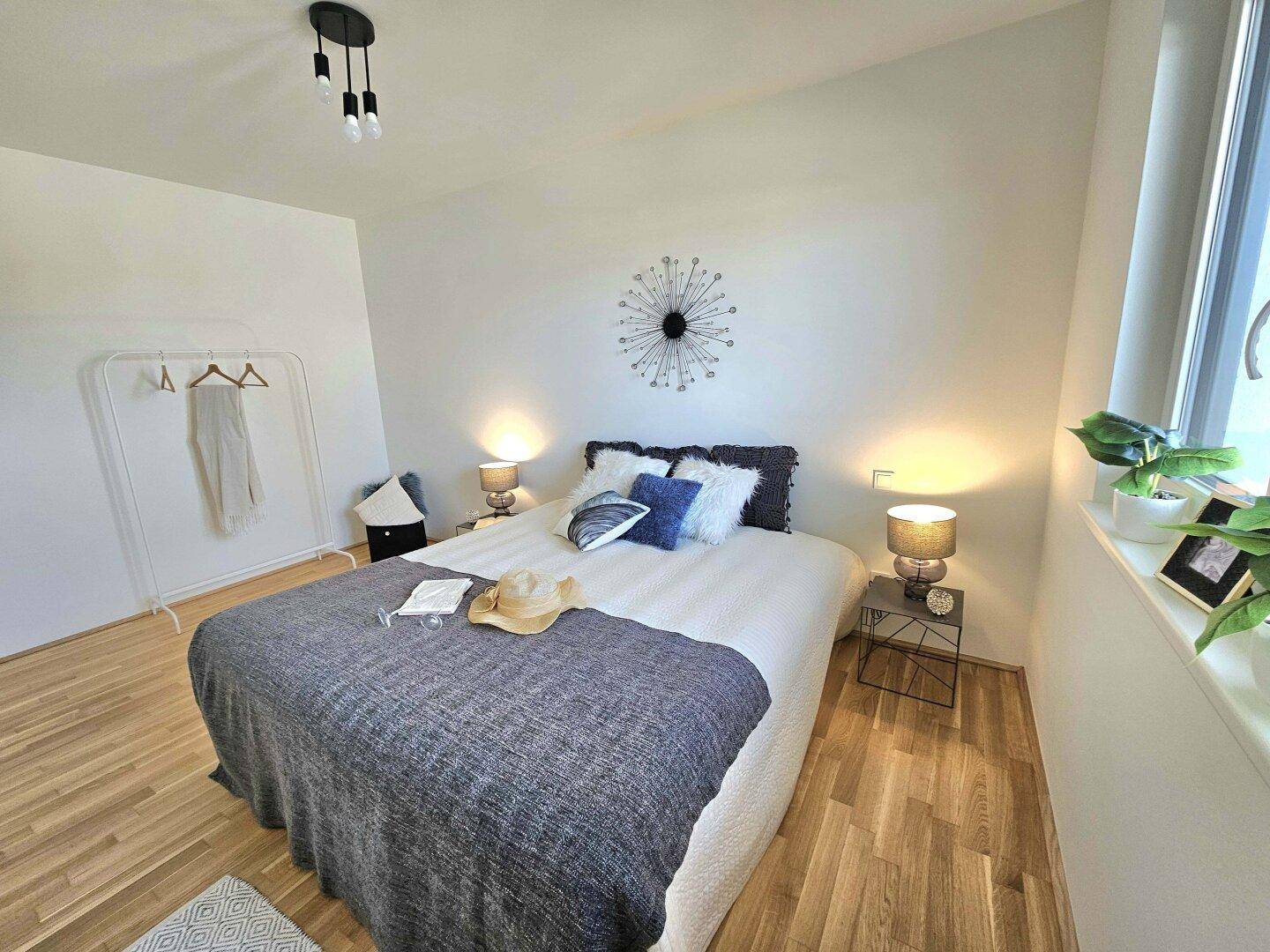 Helles Schlafzimmer mit bequemen Bett, Nachttischen und einem Fenster für Tageslicht.