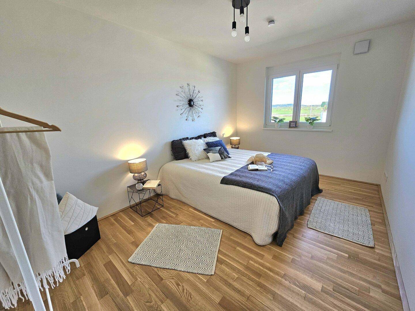 Gemütliches Schlafzimmer mit Holzboden, Doppelbett und Fenster mit Blick ins Grüne.