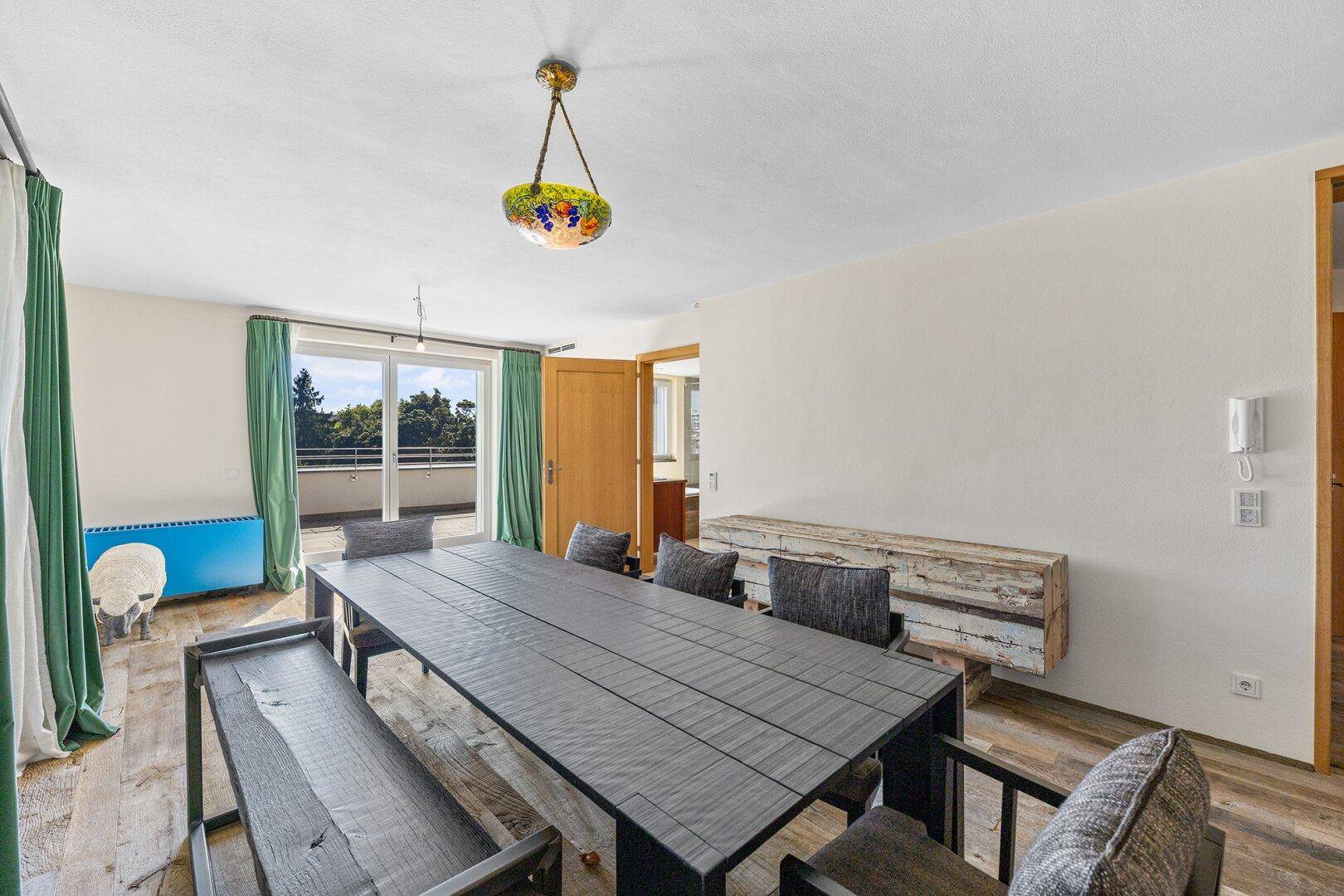 Geräumiger Essbereich mit großem Holztisch, Holzboden und Zugang zu einem Balkon.