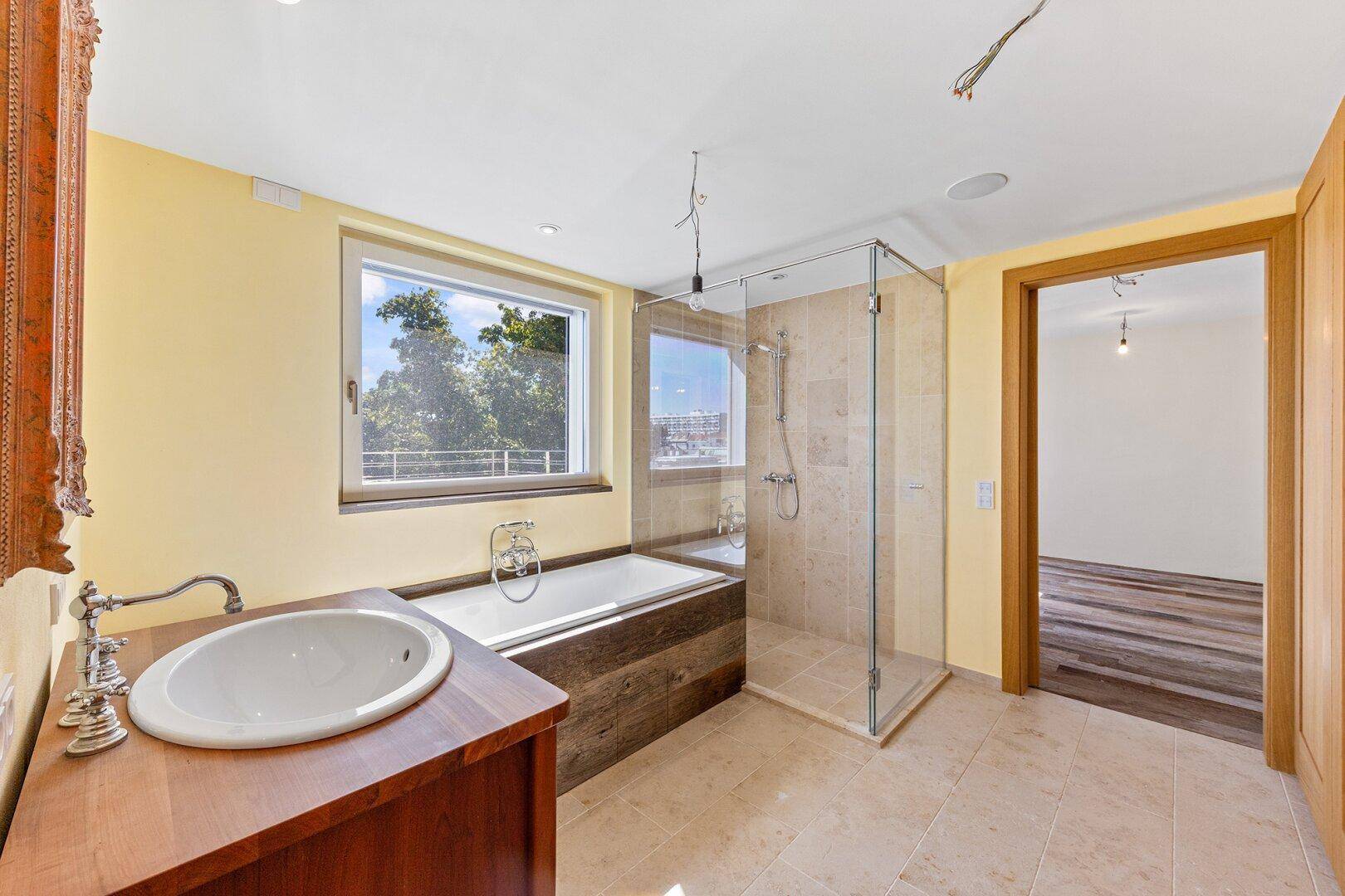 Geräumiges Badezimmer mit Badewanne, begehbarer Dusche, Einzelwaschbecken und Fenster.