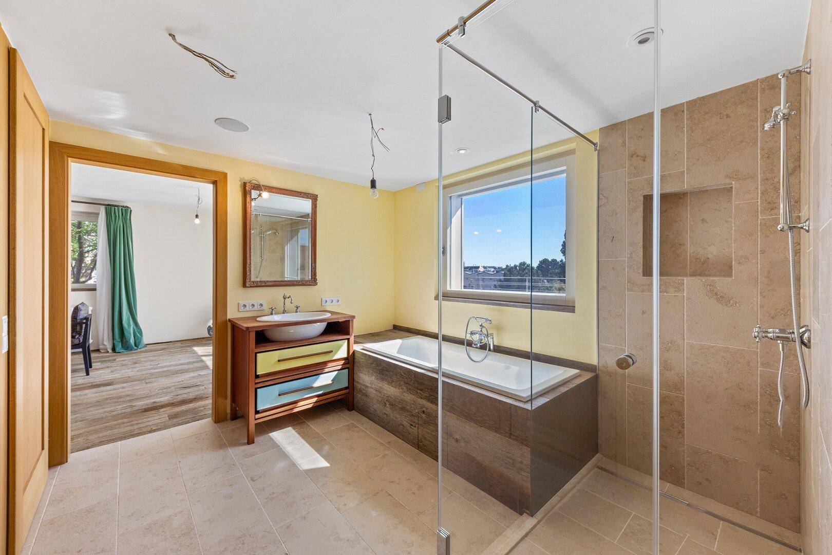 Modernes Badezimmer mit Badewanne, Glasdusche, farbenfrohem Waschtisch und Fenster.