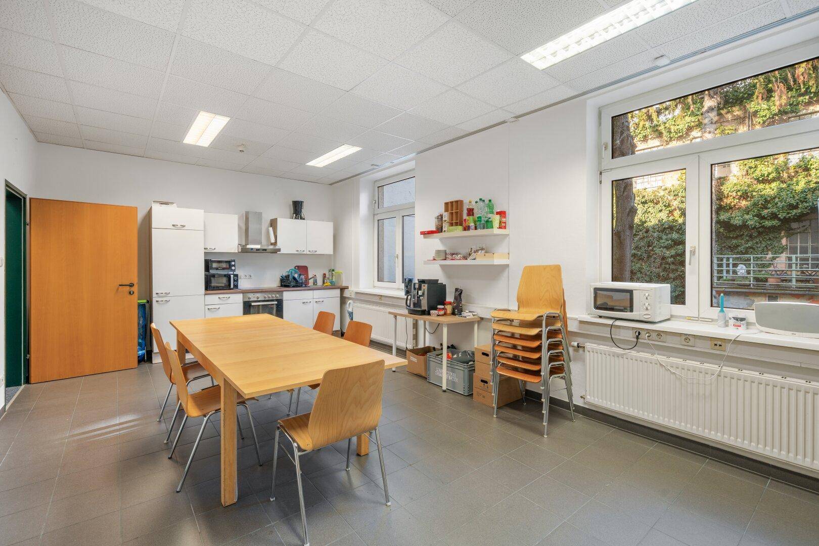 Funktionale Küche mit Essbereich, ausgestattet mit Schränken, Geräten und einem Holztisch für Pausen.