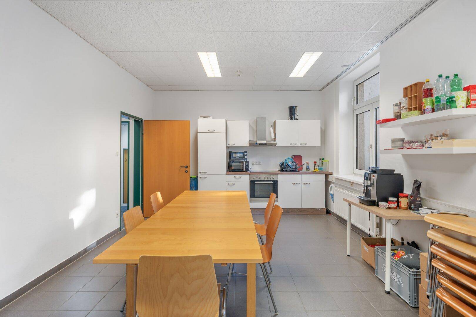 Helle und saubere Küche mit Essbereich, modernen Geräten und einem großen Holztisch für gemeinsame Mahlzeiten.