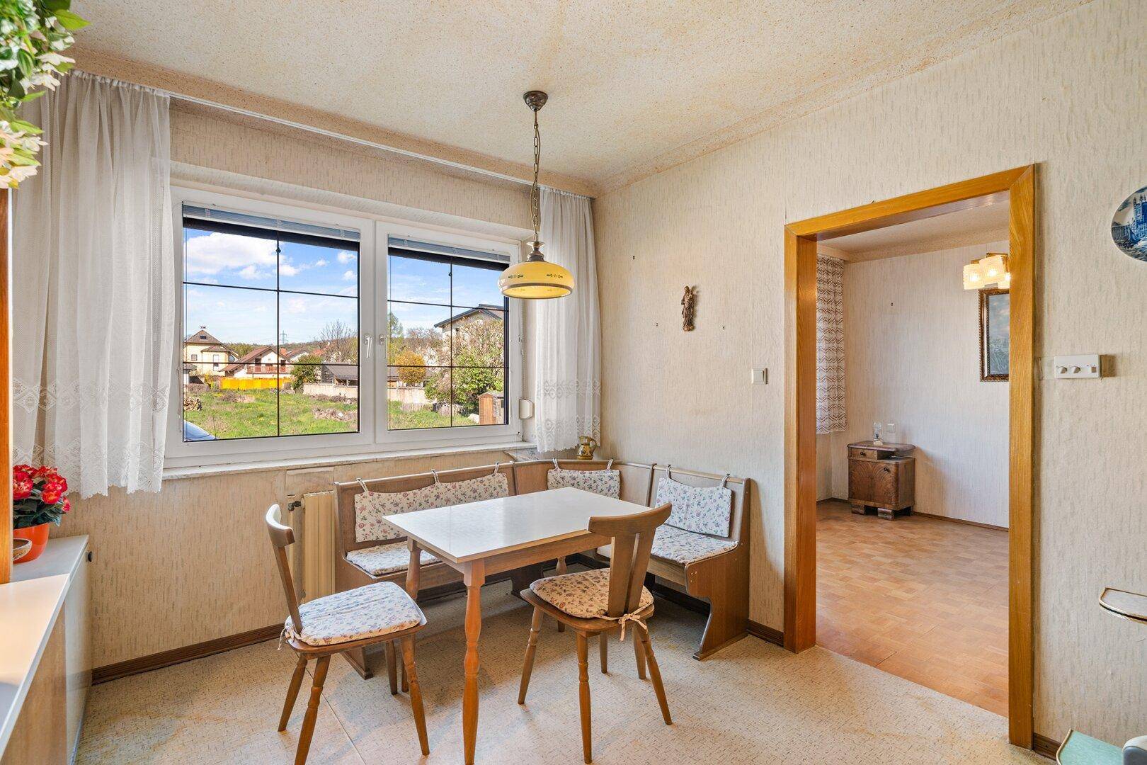 Gemütlicher Essbereich in der Küche mit traditionellen Holzmöbeln und Fensterblick.