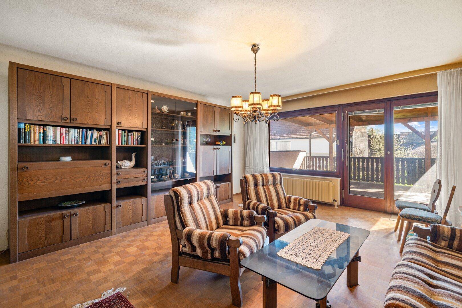 Geräumiges Wohnzimmer mit Hartholzboden, traditionellen Möbeln und Zugang zum Balkon.