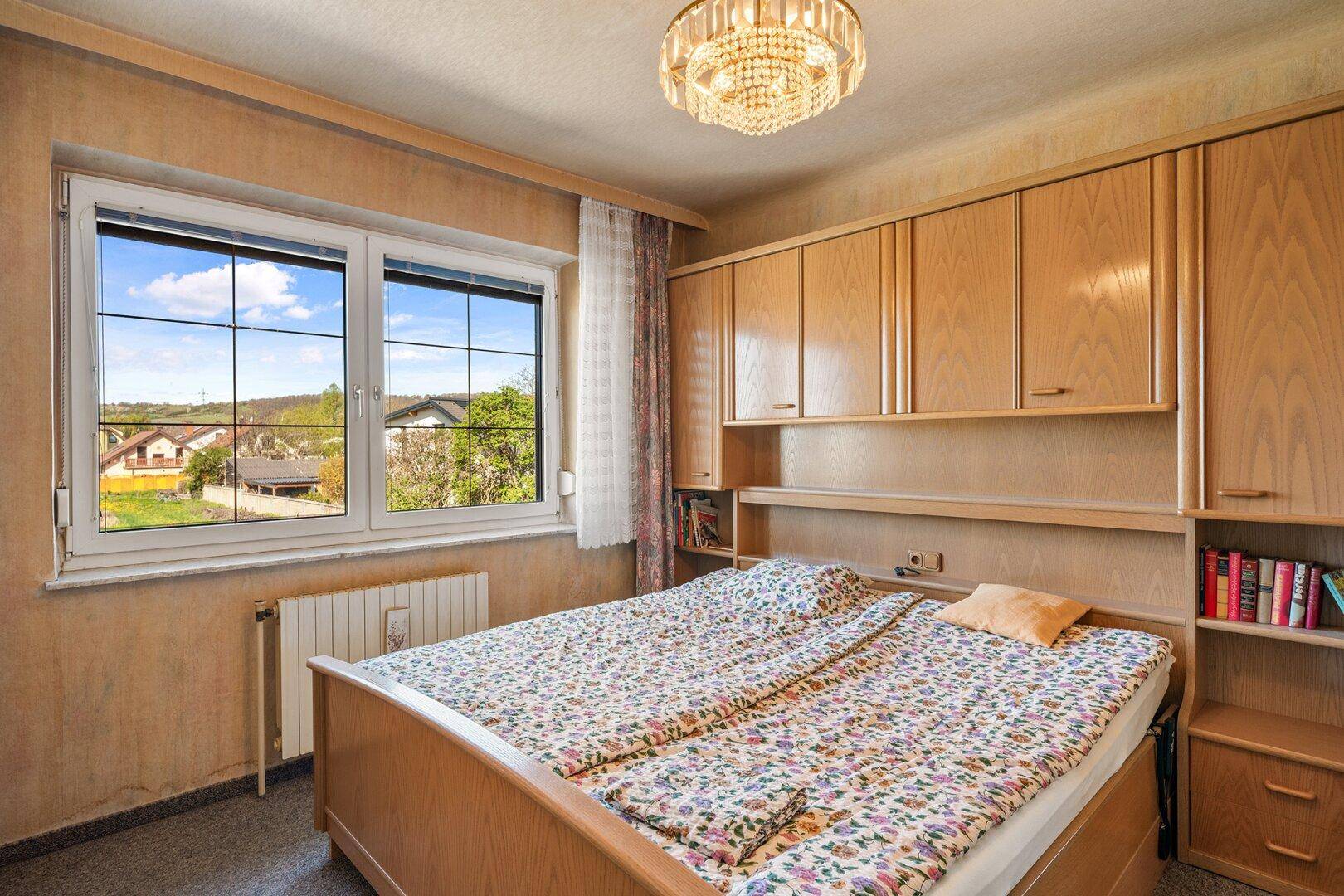 Schlafzimmer im klassischen Stil mit Einbauschränken und Blick auf die Umgebung.