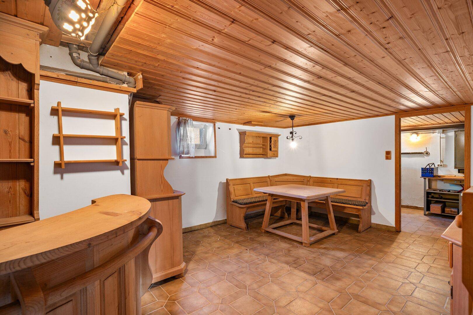 Rustikaler Kellerraum mit Holzvertäfelung, Sitzgelegenheiten und Barbereich.