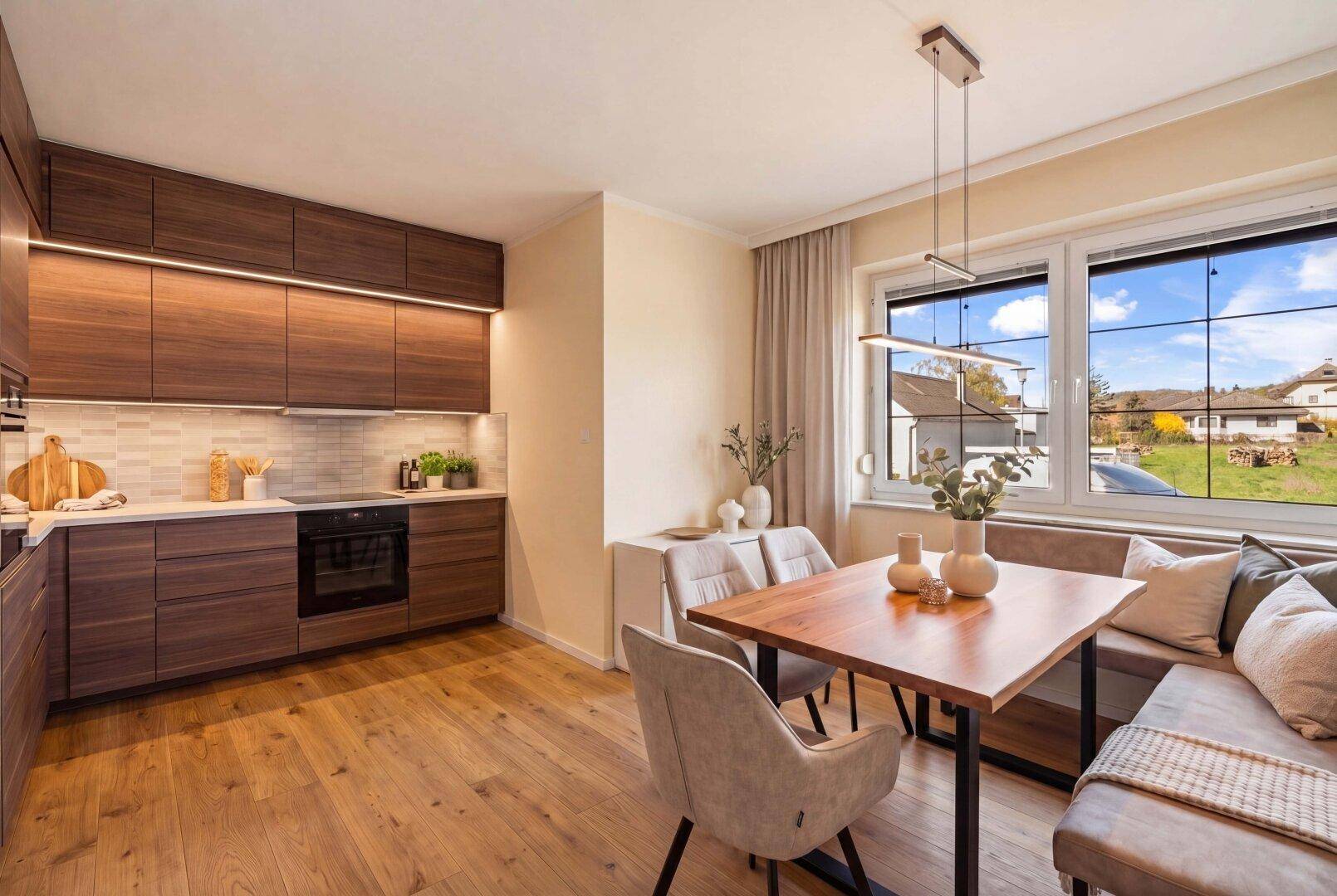 Modernisierte Küche mit dunklen Holzschränken, integriertem Essbereich und Blick ins Grüne.