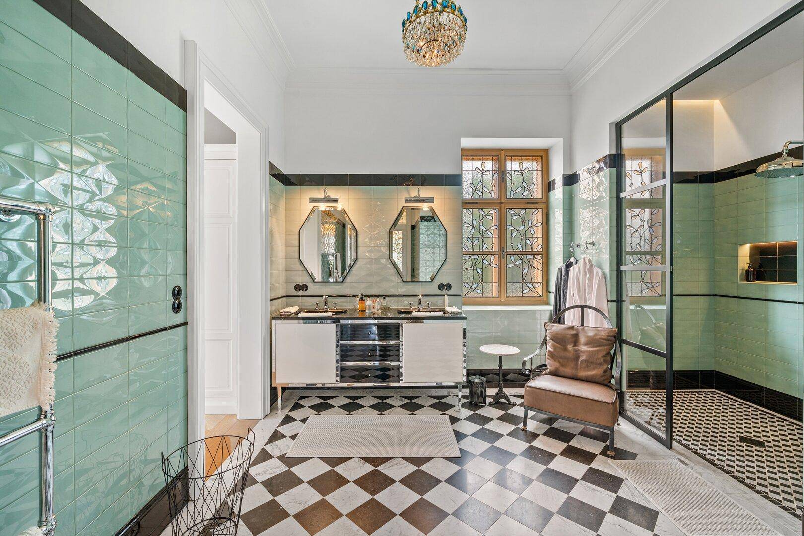 Modernes Badezimmer mit Doppelwaschbecken, großer Dusche und schwarz-weißem Fliesenboden.