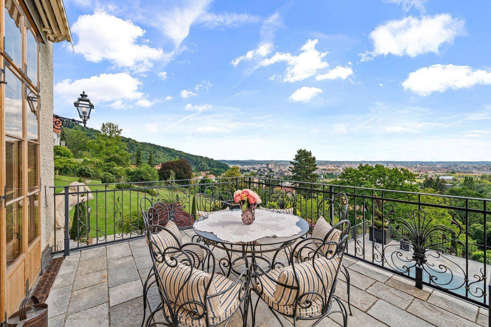 Große Terrasse mit schmiedeeisernen Möbeln und weitem Panoramablick über die Stadt und Landschaft.