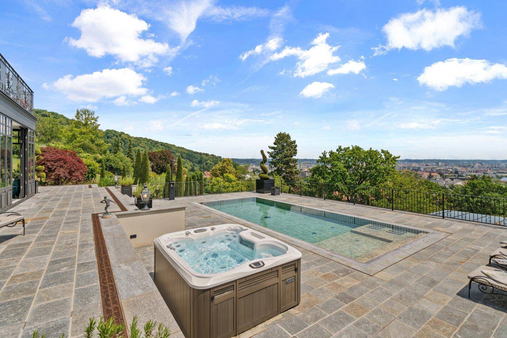 Exklusiver Außenbereich mit Pool, Whirlpool und weitläufiger Terrasse mit Panoramablick.