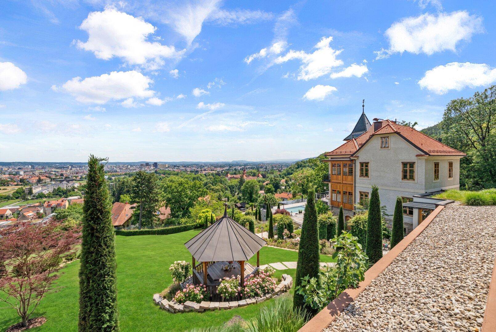 Weitläufiger Panoramablick über das Anwesen, den Garten und die Stadtlandschaft.