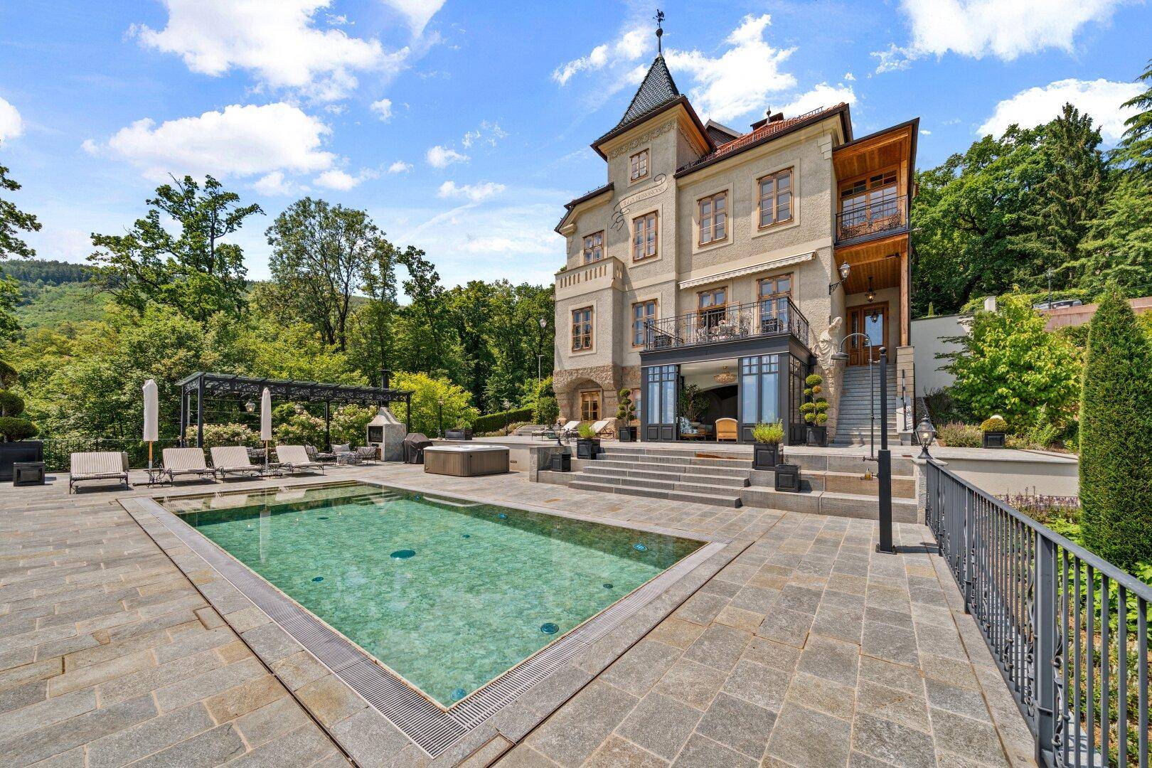 Beeindruckende Villa mit Pool, weitläufiger Terrasse und üppiger grüner Umgebung.