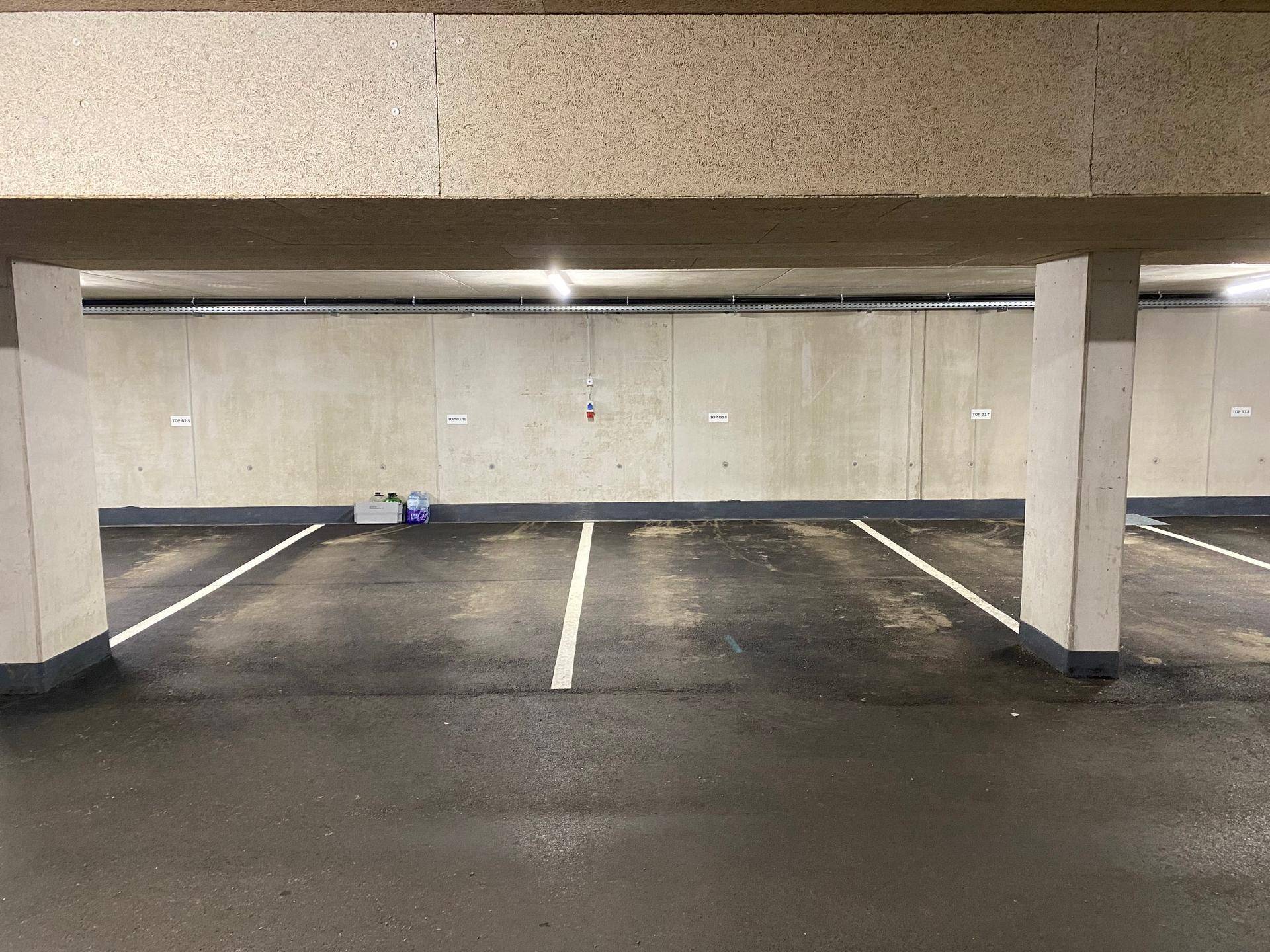 Helle Tiefgarage mit klaren Parkplatzmarkierungen und sichtbaren Betonstrukturen.
