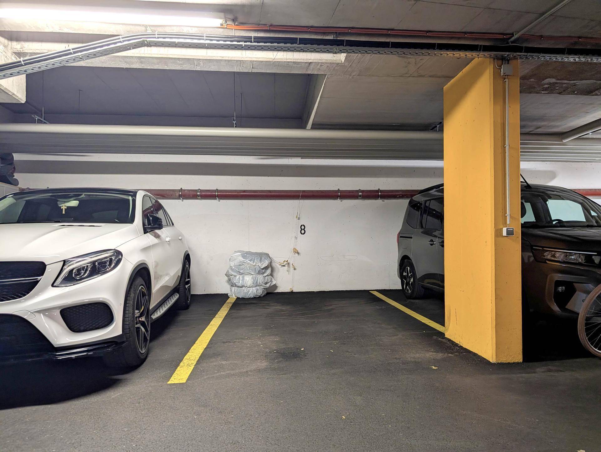 Tiefgarage mit markierten Stellplätzen und zwei geparkten Fahrzeugen.