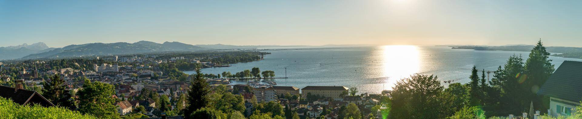 Weitläufiger Panoramablick über den See, die Stadt und die majestätischen Berge am Horizont.