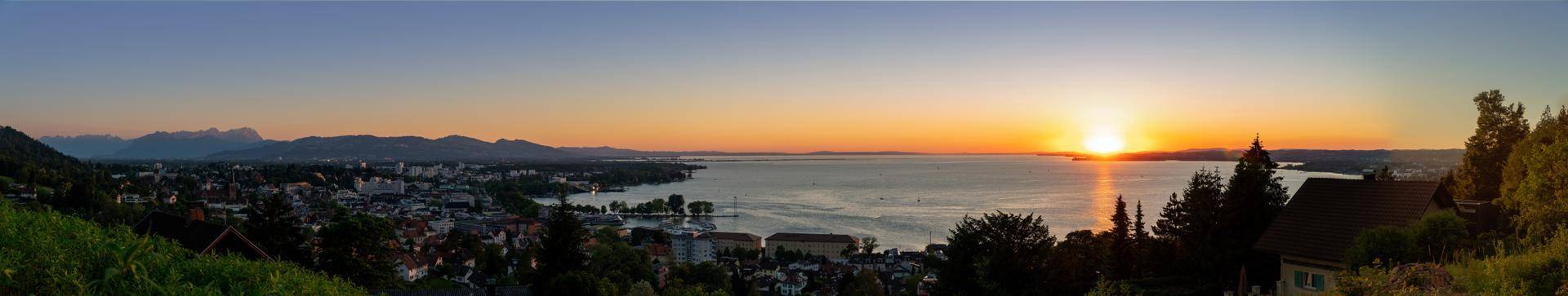 Atemberaubender Panoramablick auf die Stadt und den See bei einem leuchtenden Sonnenuntergang.