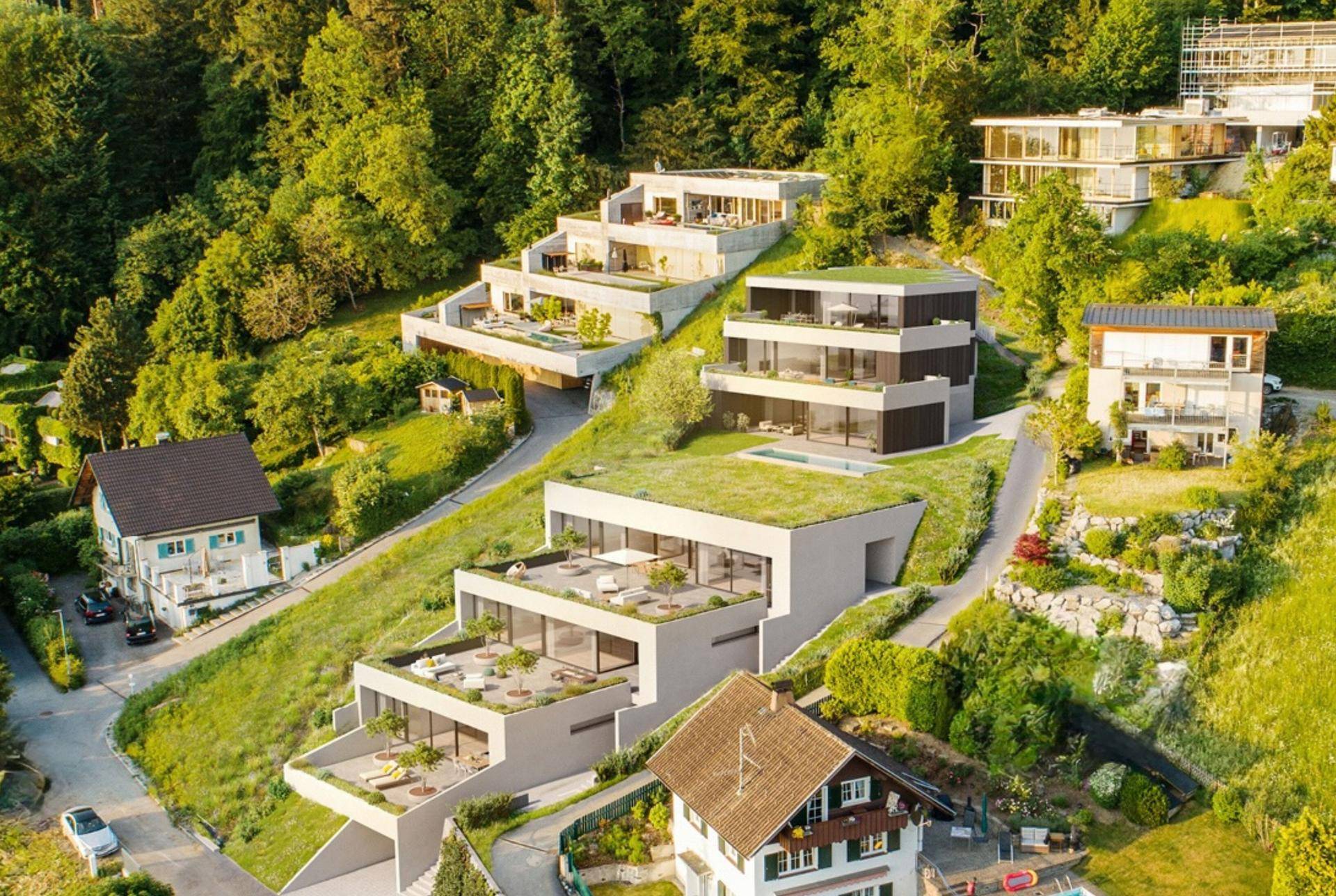 Moderne Terrassenhäuser mit Gründächern und Pools, harmonisch in die grüne Hanglandschaft integriert.