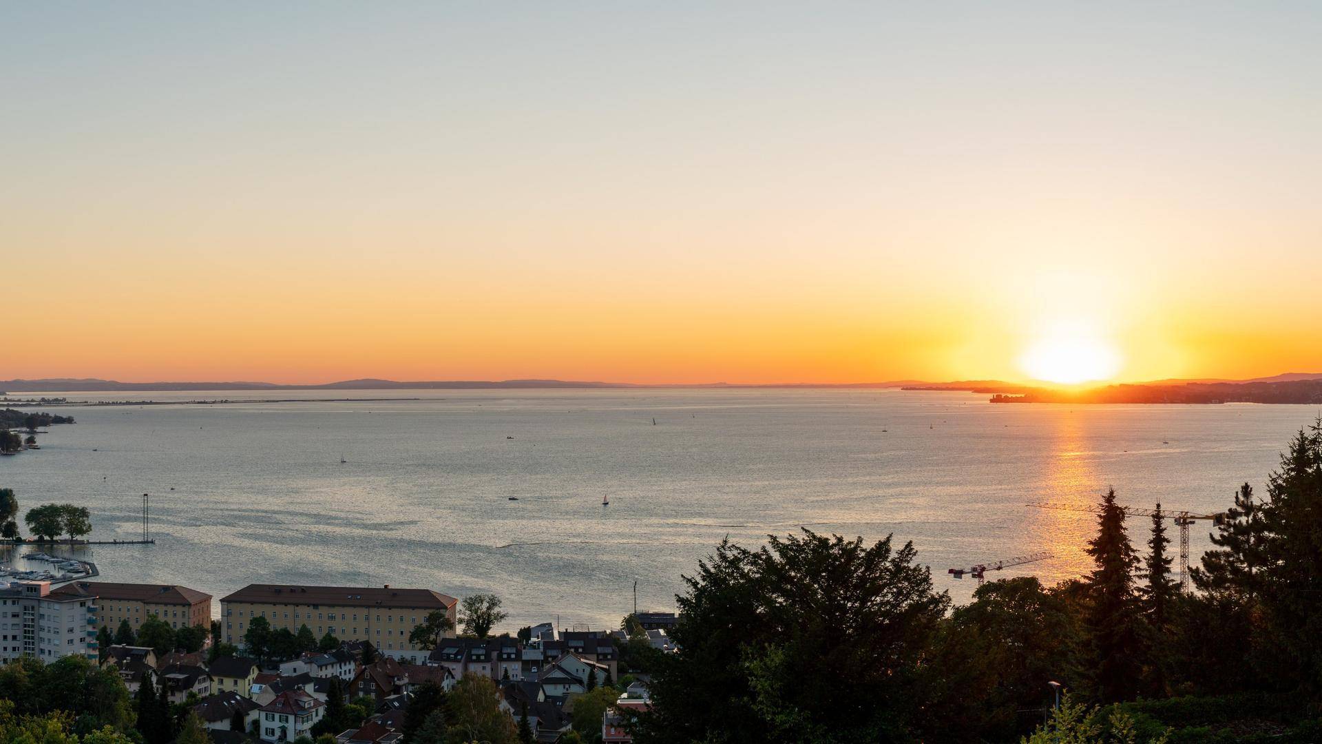 Atemberaubender Panoramablick auf einen See und eine Stadt bei Sonnenuntergang mit warmem Licht.