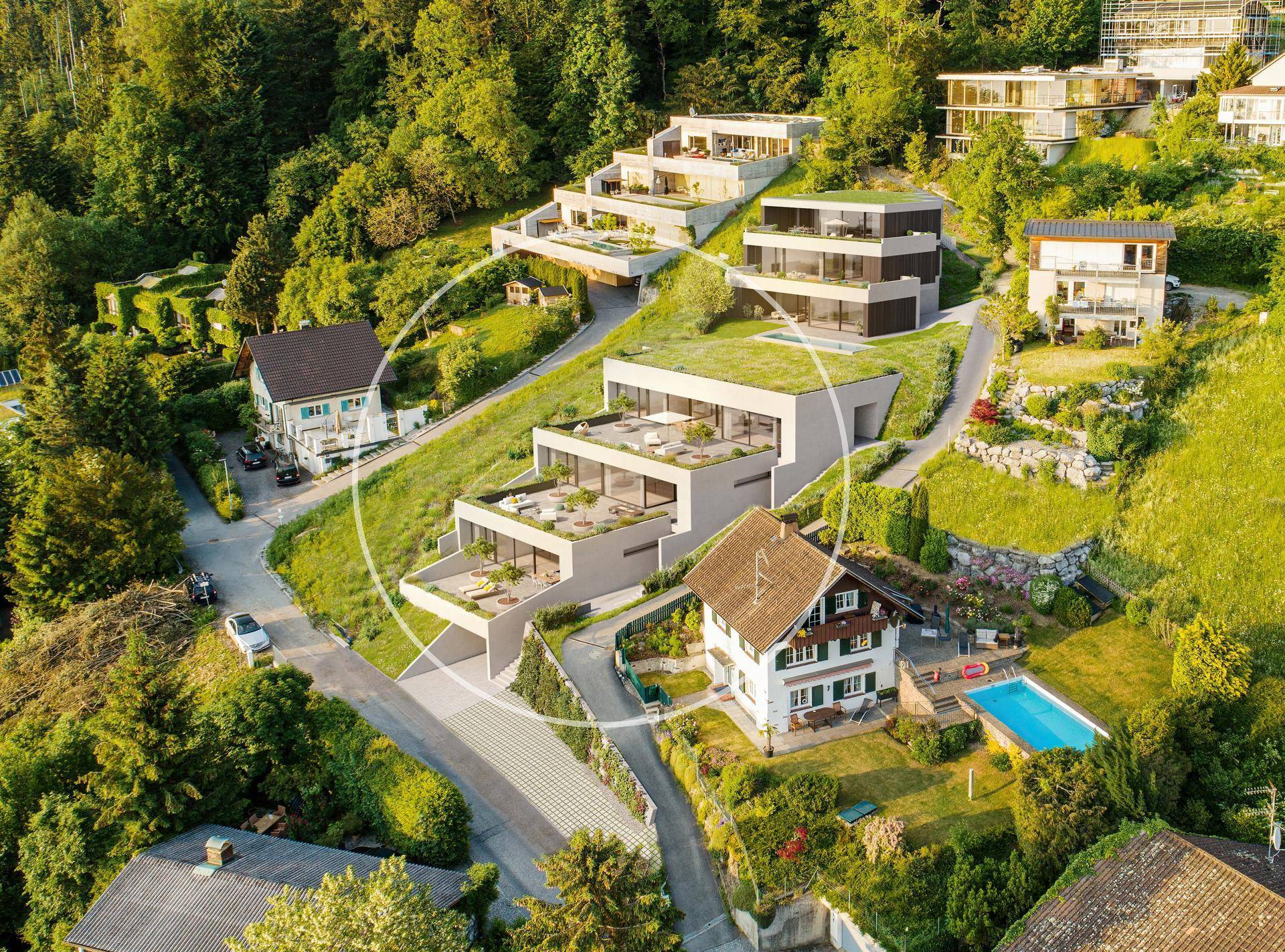 Luftaufnahme einer modernen Wohnanlage am Hang mit Terrassen und einem Pool in der Nachbarschaft.
