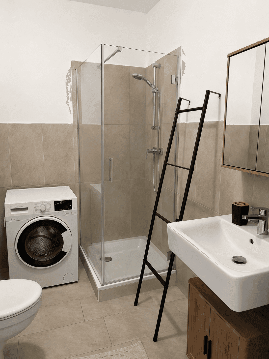 Modernes Badezimmer mit Duschkabine, Waschmaschine und Waschbecken mit Holzunterschrank.