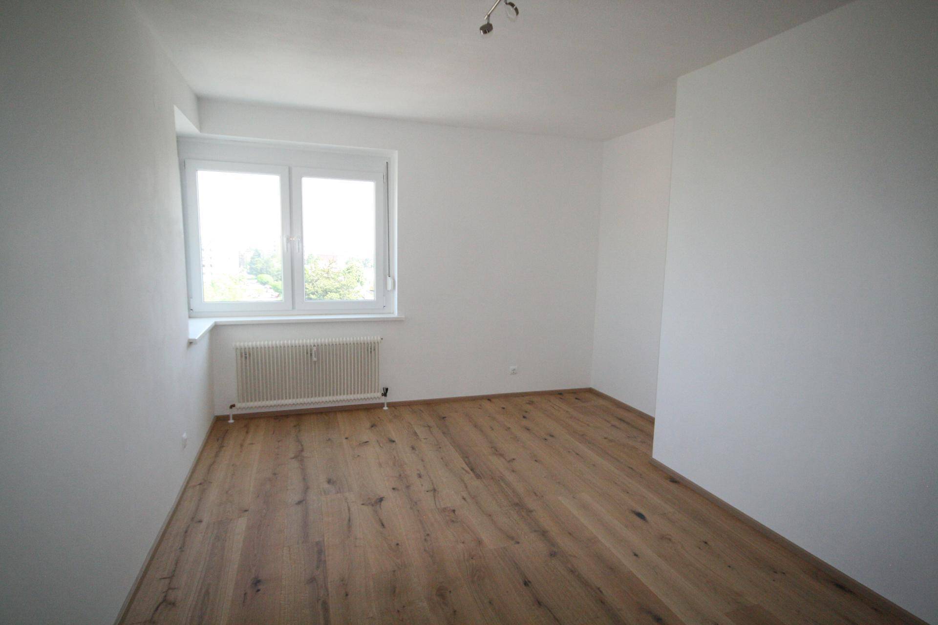 Helles Schlafzimmer mit neuem Holzboden, großen Fenstern und viel Tageslicht.