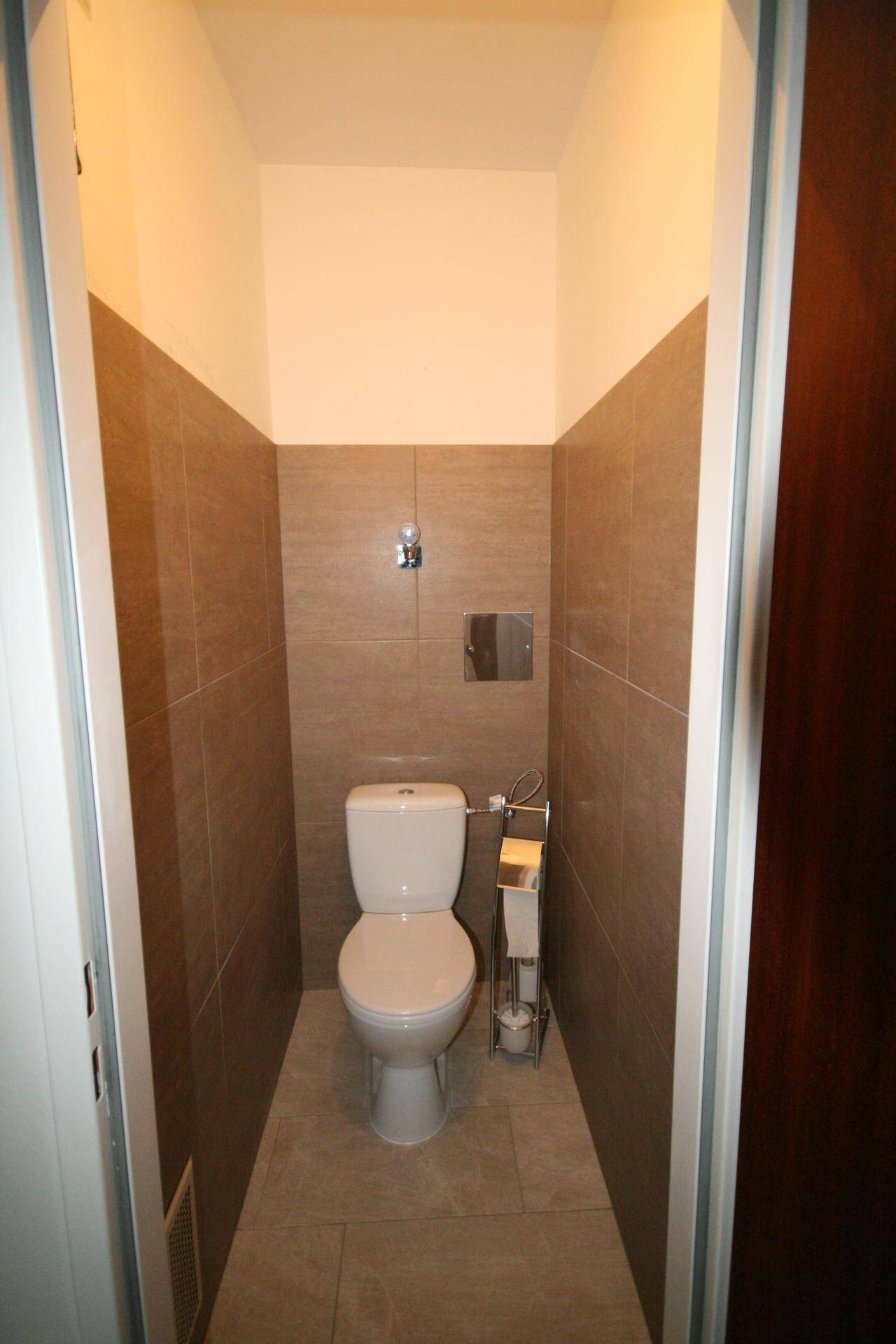 Kompaktes Gäste-WC mit modernen braunen Fliesen und wandmontierter Toilette.