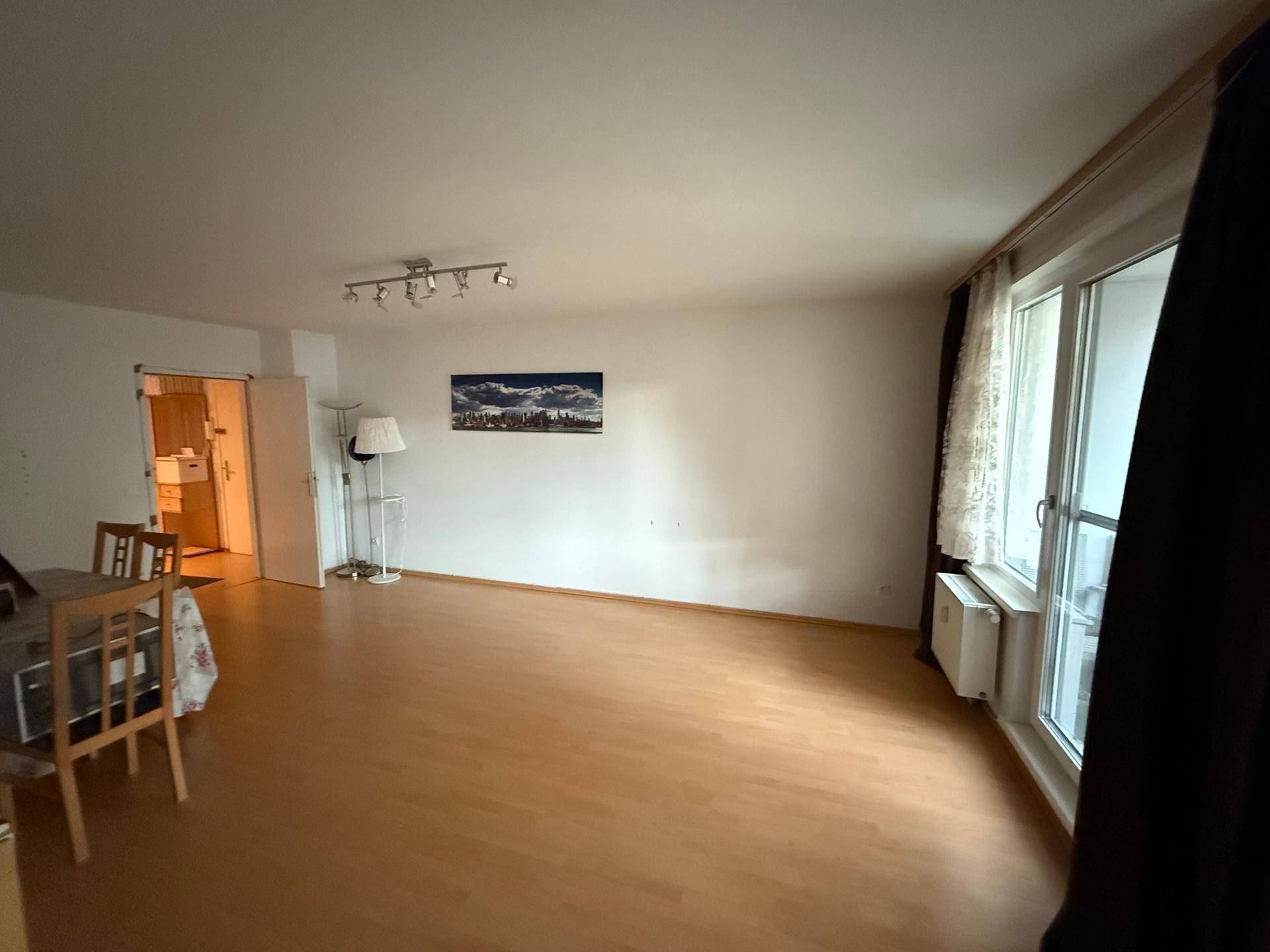 Wohn- und Essbereich mit Laminatboden, einem Esstisch und Zugang zum Balkon.