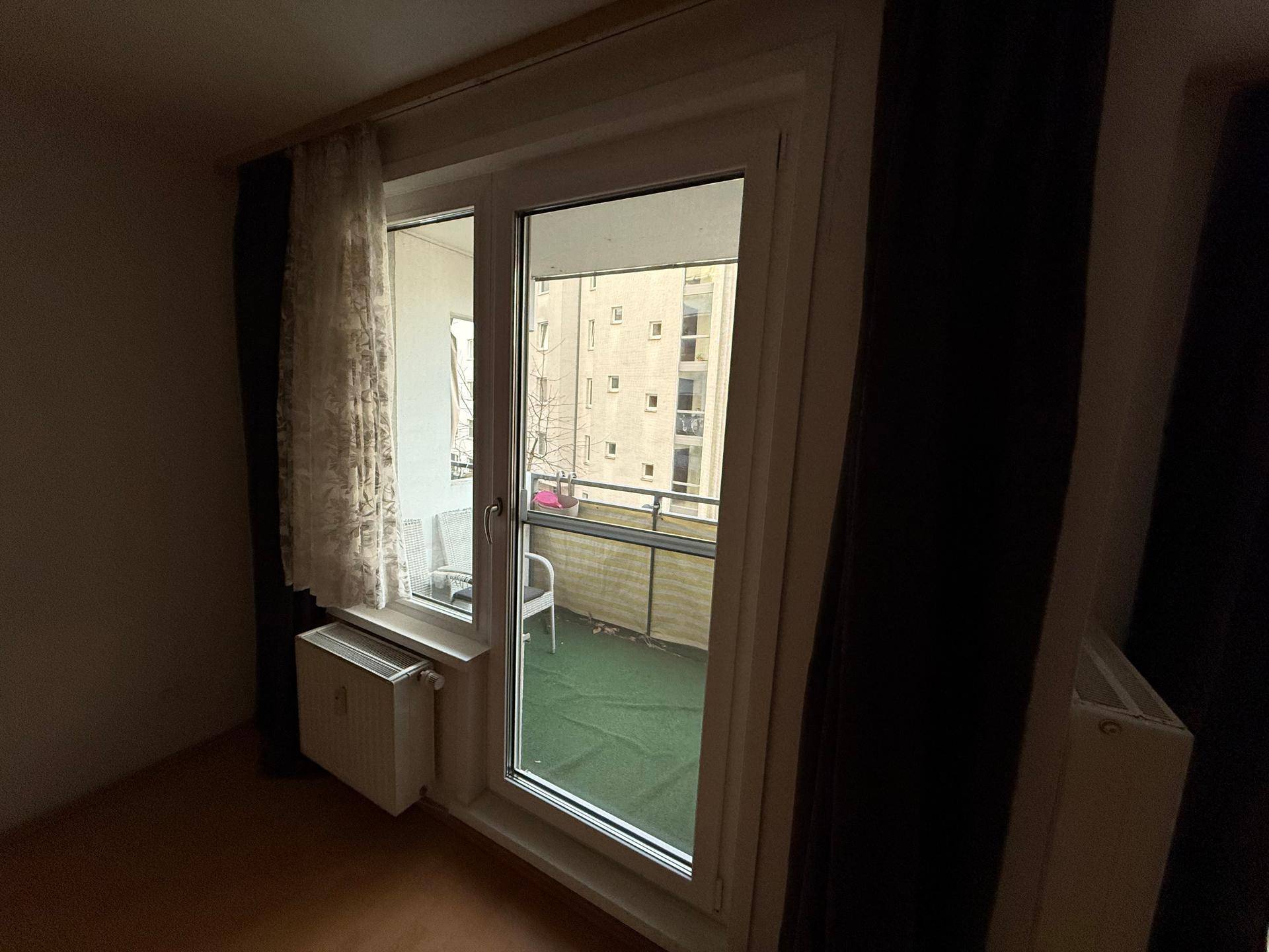 Balkontür mit Heizkörper und Blick auf den Außenbereich.