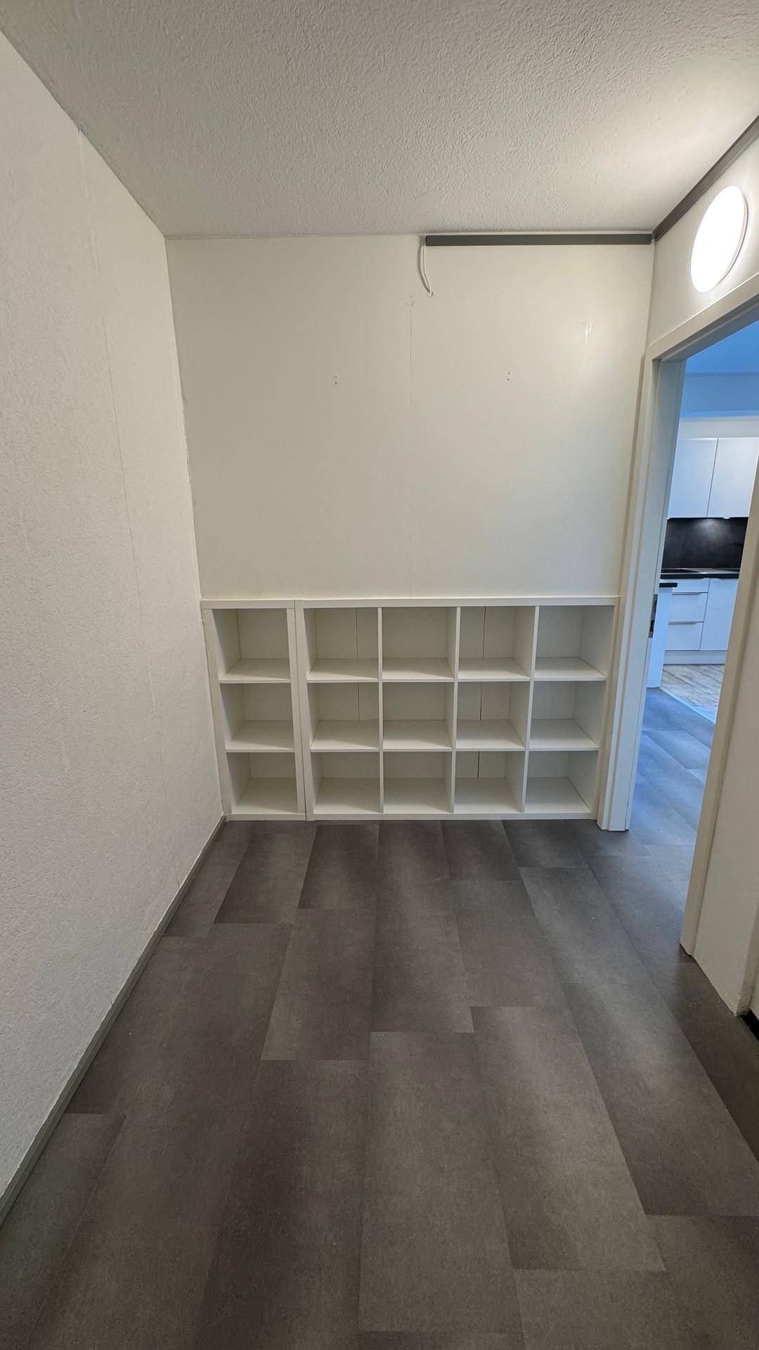 Heller Flur mit praktischen Einbauregalen und modernem Bodenbelag.