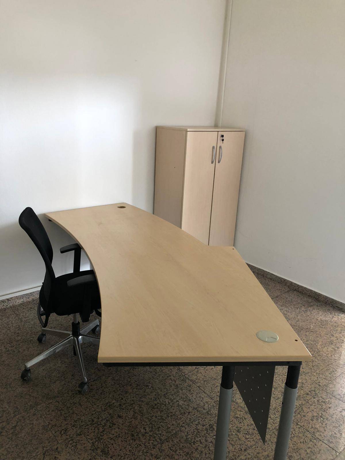 Helles Büro mit modernem, geschwungenem Schreibtisch, Bürostuhl und einem Aktenschrank an der weißen Wand.