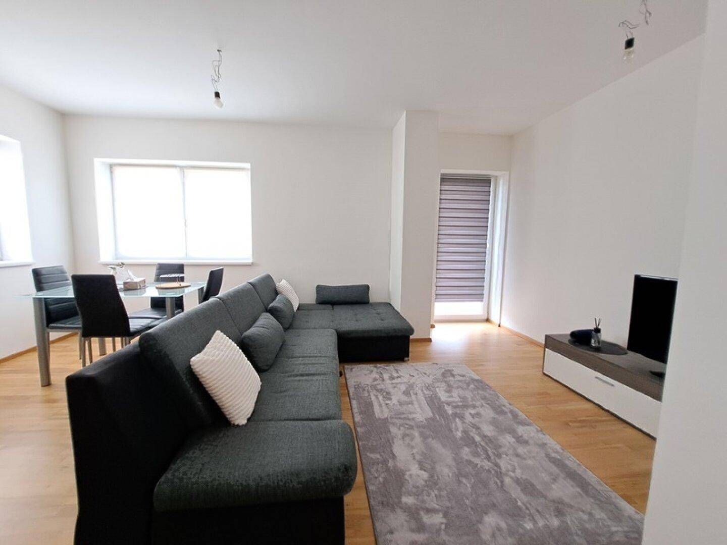 Heller Wohn- und Essbereich mit modernem Sofa, Esstisch und Zugang zur Terrasse.