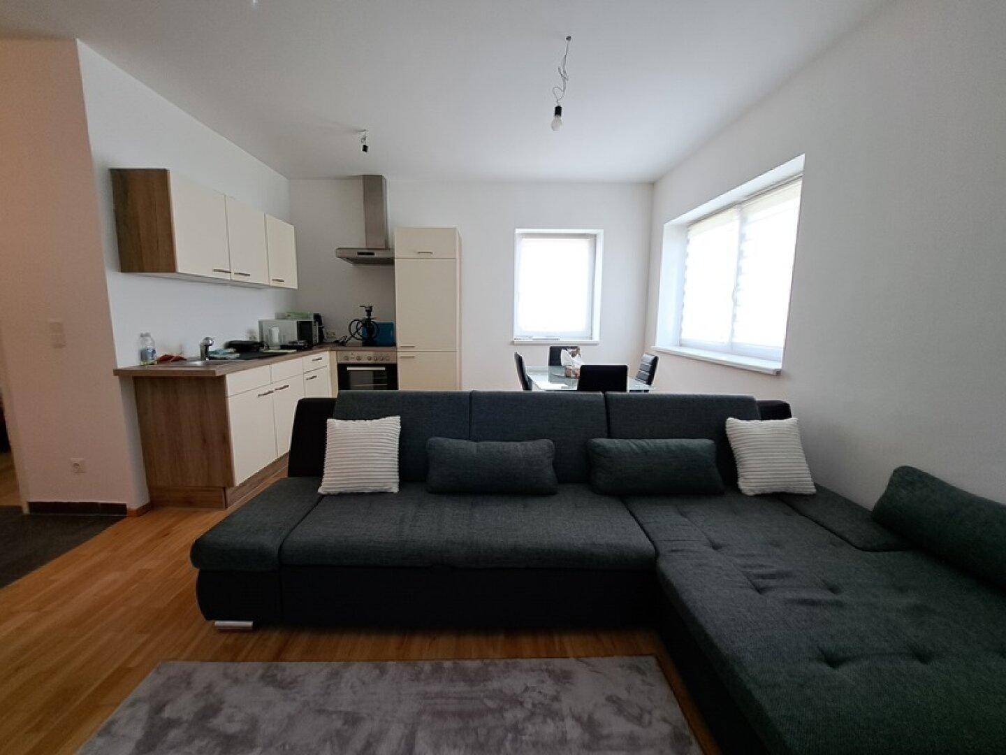 Kombinierter Wohnbereich mit offener Küche, Sofa und Essplatz, ideal für geselliges Beisammensein.