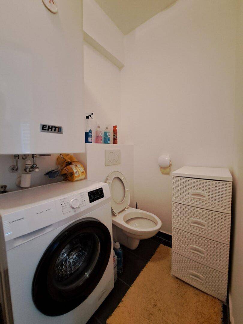 Separates WC mit Toilette und Waschmaschine, funktional und platzsparend gestaltet.