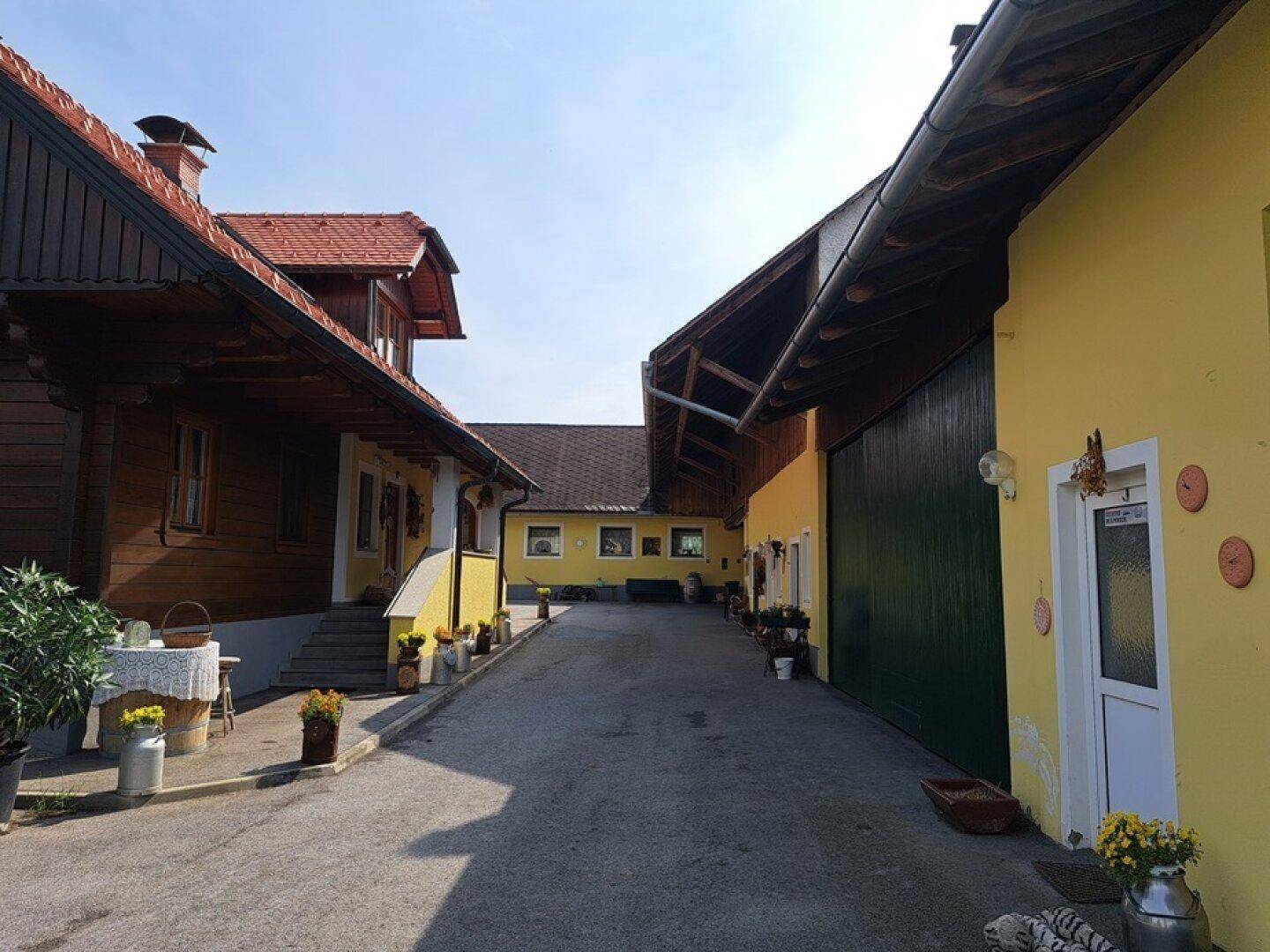 Zufahrt zwischen zwei Gebäuden mit gelber und holzverkleideter Fassade unter klarem Himmel.