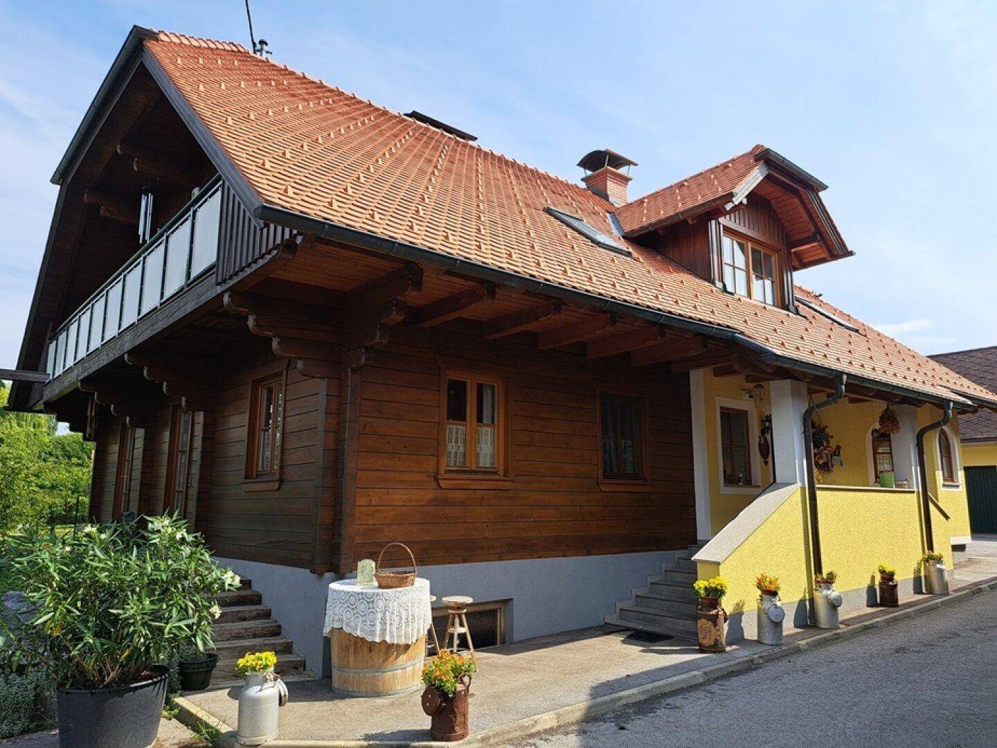 Charmantes Holzhaus mit gelben Akzenten, traditionellem Dach und kleinem Balkon.