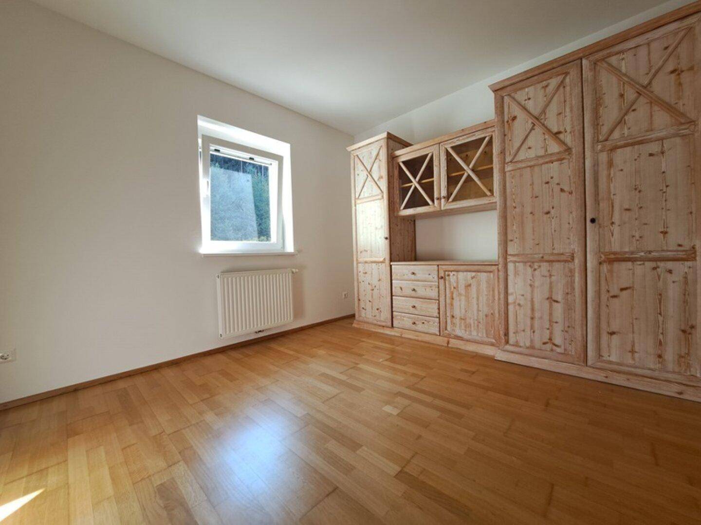 Zimmer mit Parkettboden und rustikalen Holzmöbeln, die viel Stauraum bieten.