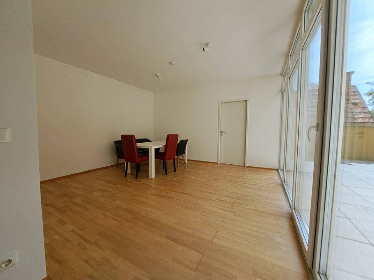 Geräumiger Essbereich mit Holzboden und großen Fenstern, die viel Tageslicht hereinlassen.