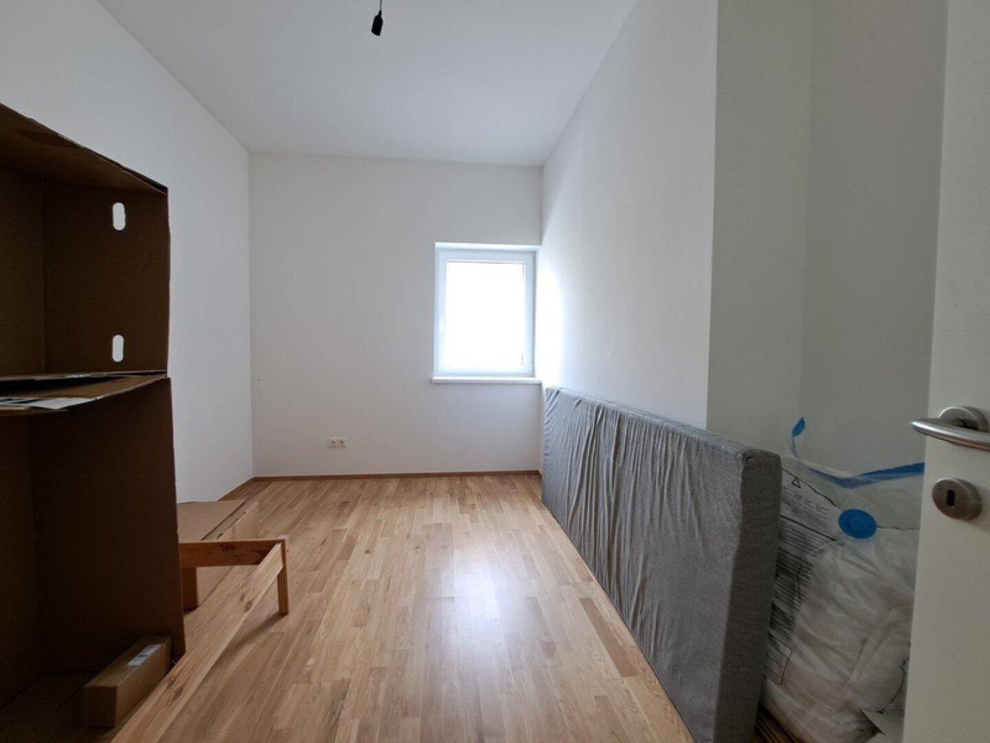 Schlafzimmer mit Holzboden und Fenster, bietet Potenzial für individuelle Gestaltung.