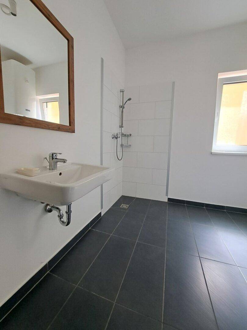 Modernes Badezimmer mit Dusche, Waschbecken und Toilette, hell und funktional gestaltet.