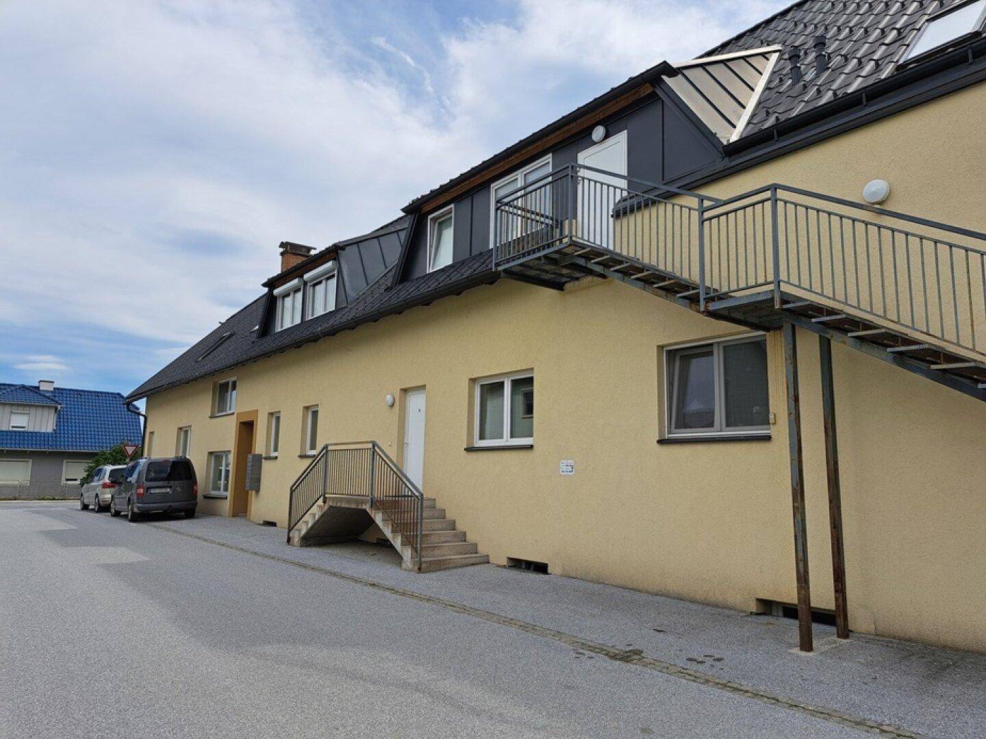 Seitenansicht des Gebäudes mit Außentreppe und mehreren Fenstern.